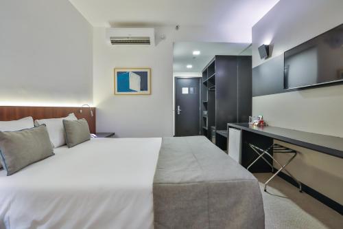 a bedroom with a large white bed and a desk at Wyndham Garden Ribeirão Preto Convention in Ribeirão Preto
