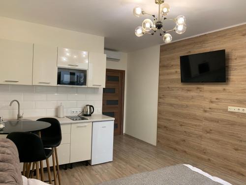 a kitchen with a table and a tv on a wall at Апартаменти-студія на Герцена in Chernivtsi