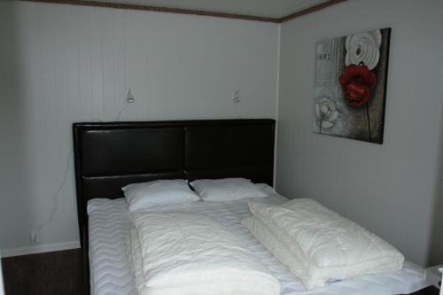 a bed with a black headboard and white pillows at Tjeldsundbrua Maritim in Evenskjer