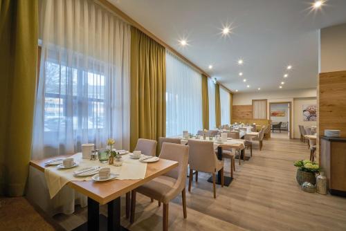 a restaurant with tables and chairs and a large window at Gästehaus Huber - Hotel Garni in Bad Füssing