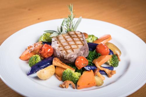 a plate of food with meat and vegetables on a table at Hostel by Randolins in St. Moritz