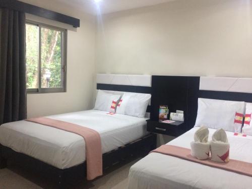 ein Schlafzimmer mit zwei Betten mit Schuhen drauf in der Unterkunft Hotel Sevilla Palenque in Palenque