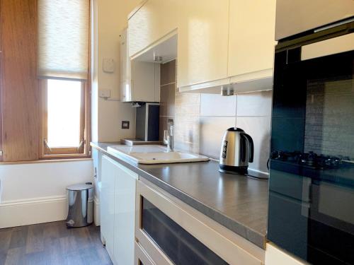 a kitchen with white cabinets and a counter top at Tay View Apartment in Dundee