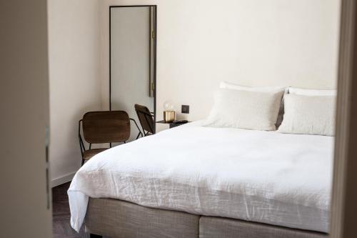 um quarto com uma cama branca e uma cadeira em B'Guest Sleep & Retreat em Bruges