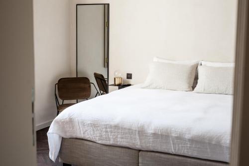 a bedroom with a white bed and a chair at B'Guest Sleep & Retreat in Bruges