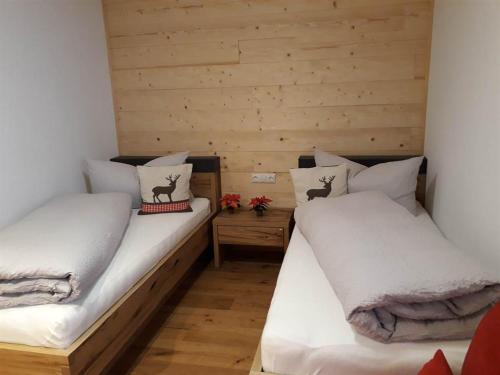 2 łóżka pojedyncze w pokoju z drewnianymi ścianami w obiekcie Gästehaus Kessler w mieście Gaschurn