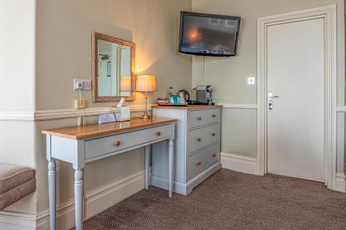 a room with a dresser with a mirror and a desk at Botany Bay Hotel in Broadstairs