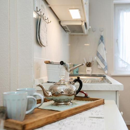 a tea kettle and two cups on a kitchen counter at Strandläufernest in Tinnum