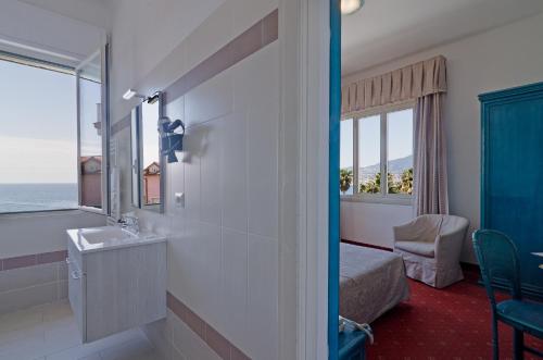 baño con lavabo, cama y ventana en Hotel Ariston Montecarlo, en San Remo