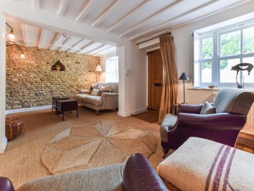 a living room with couches and a stone wall at Browns Cottage in Chipping Norton