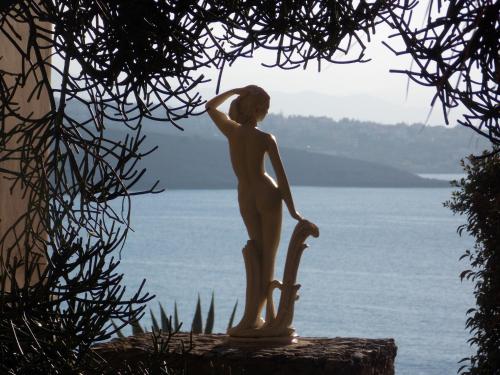 a statue of a woman standing on a rock near the water at Nostalgia Villas in Tersanas