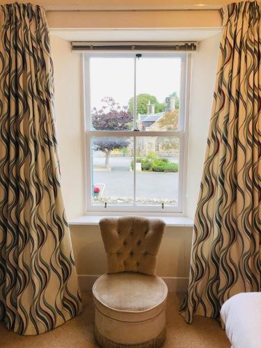 a chair in front of a window with curtains at The Aberdeen Arms Hotel in Tarves