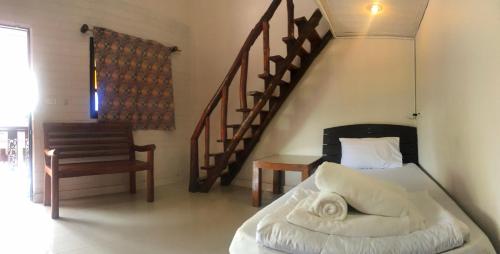 a bedroom with a bed and a chair and a staircase at Baan Lanna Resort in Chon Buri
