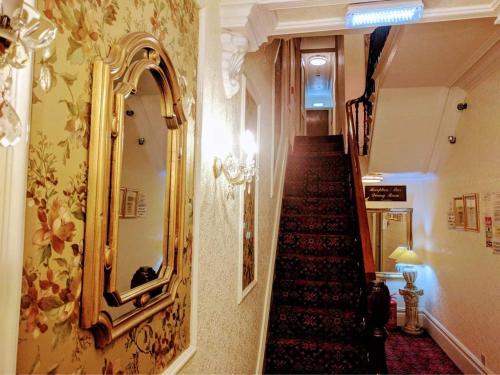 a hallway with a staircase with a mirror on the wall at Gleneagles - Albert Road in Blackpool