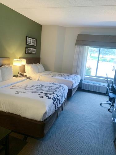 a hotel room with two beds and a window at Sleep Inn & Suites Queensbury - Lake George in Queensbury