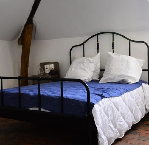 a bed with blue sheets and white pillows at Au pied du château in Saint-Aignan