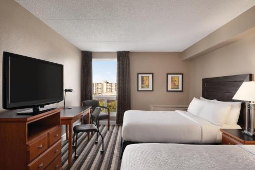 a hotel room with two beds and a television at Royal Hotel Regina, Trademark Collection by Wyndham in Regina