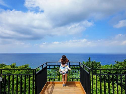 a woman standing on top of a staircase looking at the ocean at 濱境行旅 Begin Inn in Xiaoliuqiu