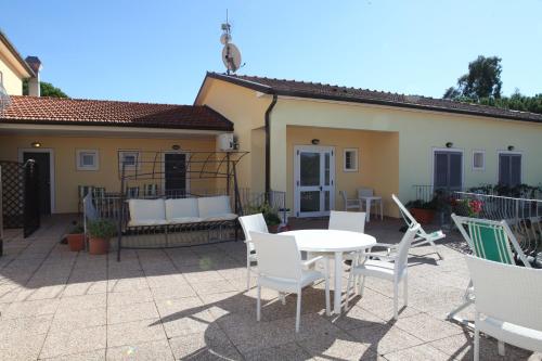 a patio with a table and chairs and a house at Hotel Villa Wanda in Porto Azzurro