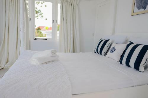 Cama blanca con almohadas azules y blancas y ventana en Ocean Front Property - Villa 5 Aruba Stunning, en Savaneta