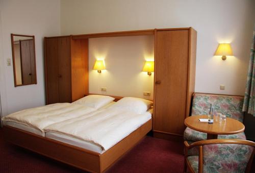 a bedroom with a bed and a table and a chair at Hotel Meyn in Soltau