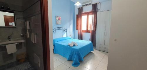Un dormitorio con una cama azul con toallas. en Costa Gaia Rooms, en San Vito lo Capo