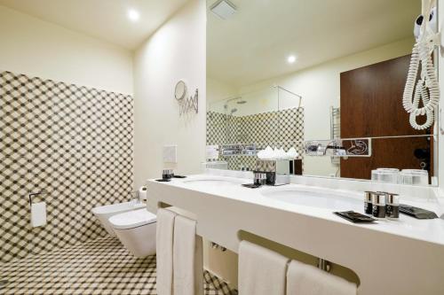 Sintra Boutique Hotel في سينترا: حمام مغسلتين ومرحاض ومرآة