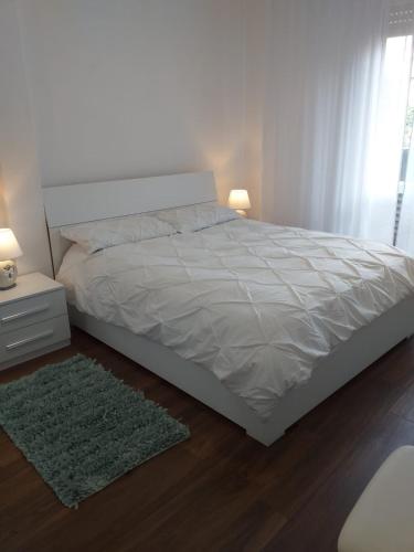 a bedroom with a white bed with a green rug at Sesto Calende Centro in Sesto Calende