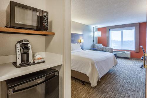 a hotel room with a bed with a tv on a wall at Holiday Inn Express & Suites O'Fallon-Shiloh by IHG in Shiloh