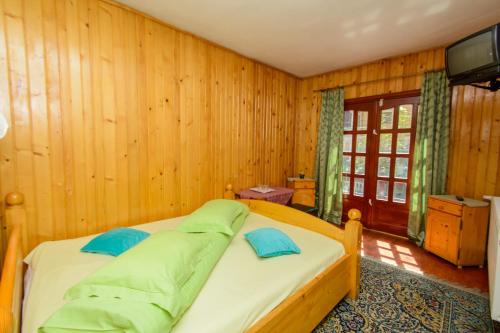 a bedroom with wooden walls and a bed with blue pillows at Rem's Pension in Râşnov