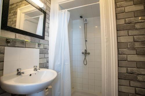 a bathroom with a sink and a shower with a mirror at The Carlton Hotel in Folkestone