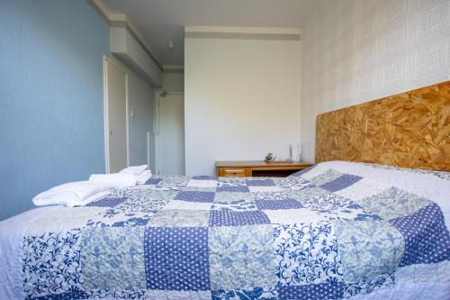 a bedroom with a blue and white quilt on a bed at The Carlton Hotel in Folkestone