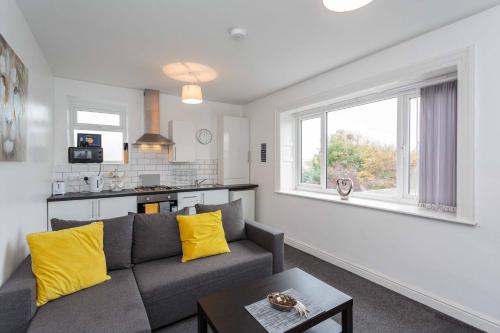 Cherry Property - Pineapple Suite في بلاكبول: غرفة معيشة مع أريكة رمادية ووسائد صفراء