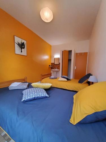 two beds in a room with yellow and blue at Chez Jollyjune, à moins d'une heure du Mont Saint Michel in Champeaux
