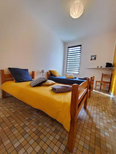 a bedroom with two beds with yellow sheets and blue pillows at Chez Jollyjune, à moins d'une heure du Mont Saint Michel in Champeaux