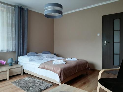 - une chambre avec un grand lit et une chaise dans l'établissement Apartamenty ,,Trzy Sosny'' Rymanów-Zdrój, à Rymanów-Zdrój