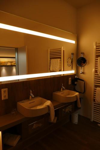 a bathroom with two sinks and a large mirror at Meyn's Apartments & Hotel in Soltau