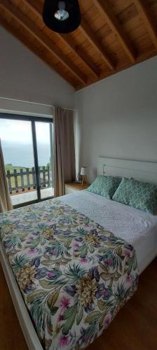 a bedroom with a large bed with a large window at Susete Village in São Roque do Pico