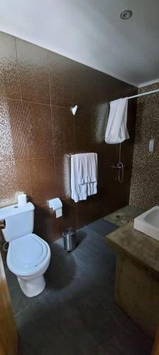 a bathroom with a toilet and a sink and towels at Susete Village in São Roque do Pico