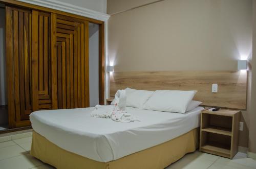 um quarto com uma cama grande e uma cabeceira em madeira em Aram Ouro Branco Hotel em Maceió