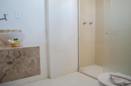 uma casa de banho com um chuveiro, um WC e um lavatório. em Aram Ouro Branco Hotel em Maceió