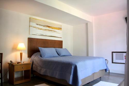 a bedroom with a bed with blue sheets and a lamp at Pousada Golf Village in Itaipava