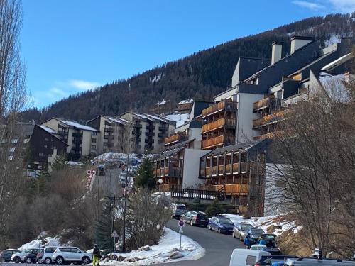 a building with cars parked in a parking lot at Studio Les Marmottes Bleues PRALOUP 1500 in Uvernet-Fours