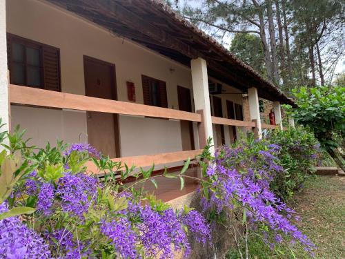 a house with purple flowers in front of it at Pousada & Camping Serras Verdes in Conservatória