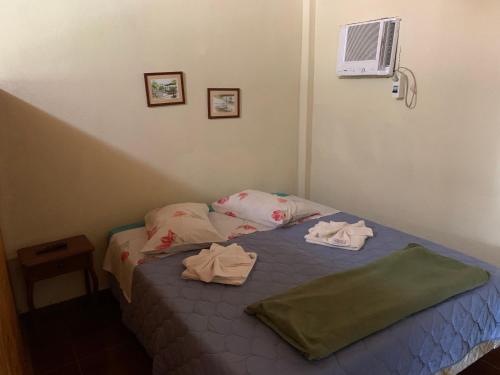 a bedroom with a bed with two towels on it at Pousada & Camping Serras Verdes in Conservatória