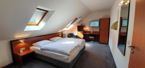 Habitación de hotel con cama y escritorio en Hotel Hillegosser Hof, en Bielefeld