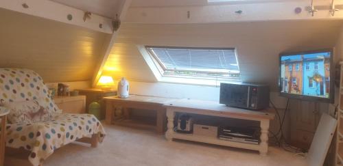 een kleine kamer met een bureau, een tv en een stoel bij Le studio fridge tv microwave, in Chester