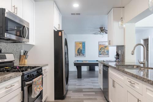 a kitchen with white cabinets and a black refrigerator at Purely Pompano, Pool, Water front, Paddleboard, Beach, 5 bedroom 3 bath in Pompano Beach