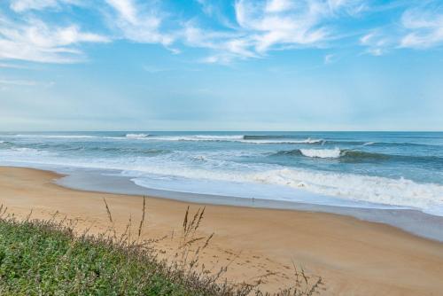 a sandy beach with waves in the ocean at Gypsea Rose in Southern Shores