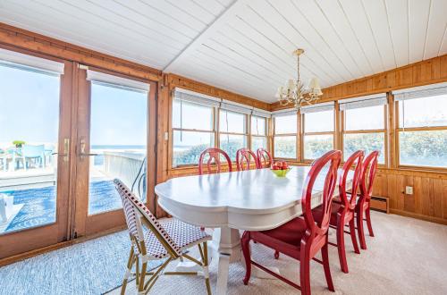 a dining room with a white table and red chairs at Gypsea Rose in Southern Shores